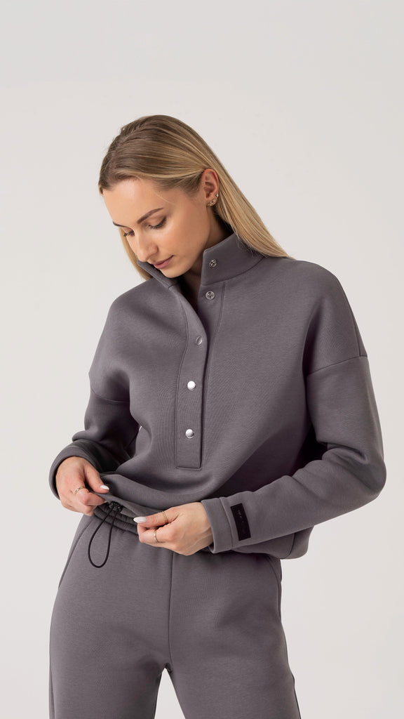 Silts pelēks sieviešu treniņtērps ar pūkainu odere, pogām un elastīgu jostasvietu.